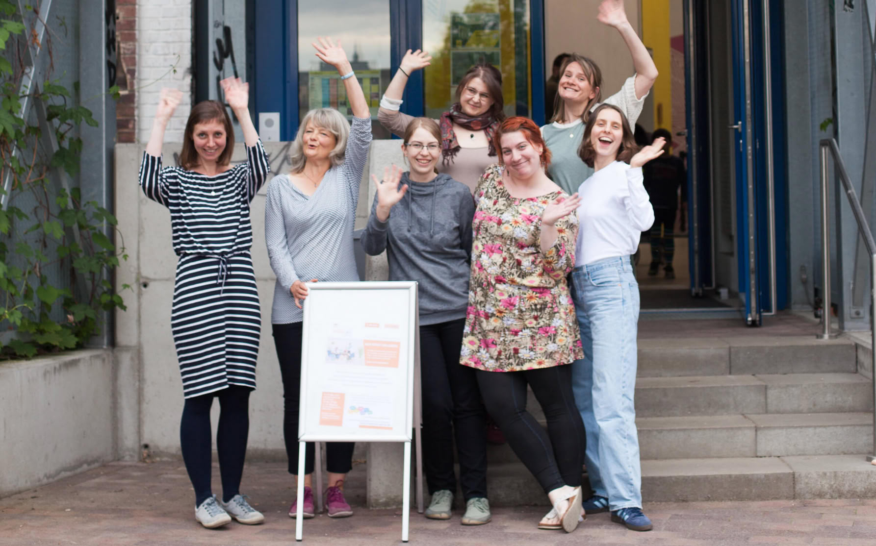 Das Team des Erzählcafés, die Hebammen Friederike Scholz, Loryn Luh sowie vier engagierte Mütter: Ulrike Knoll, Laura Faust-Kretschmer, Nele Schwarznegger und Patricia Huber und Kristin Liedtke, stehen nebeneinander vor dem Eingang und blicken freundlich in die Kamera.